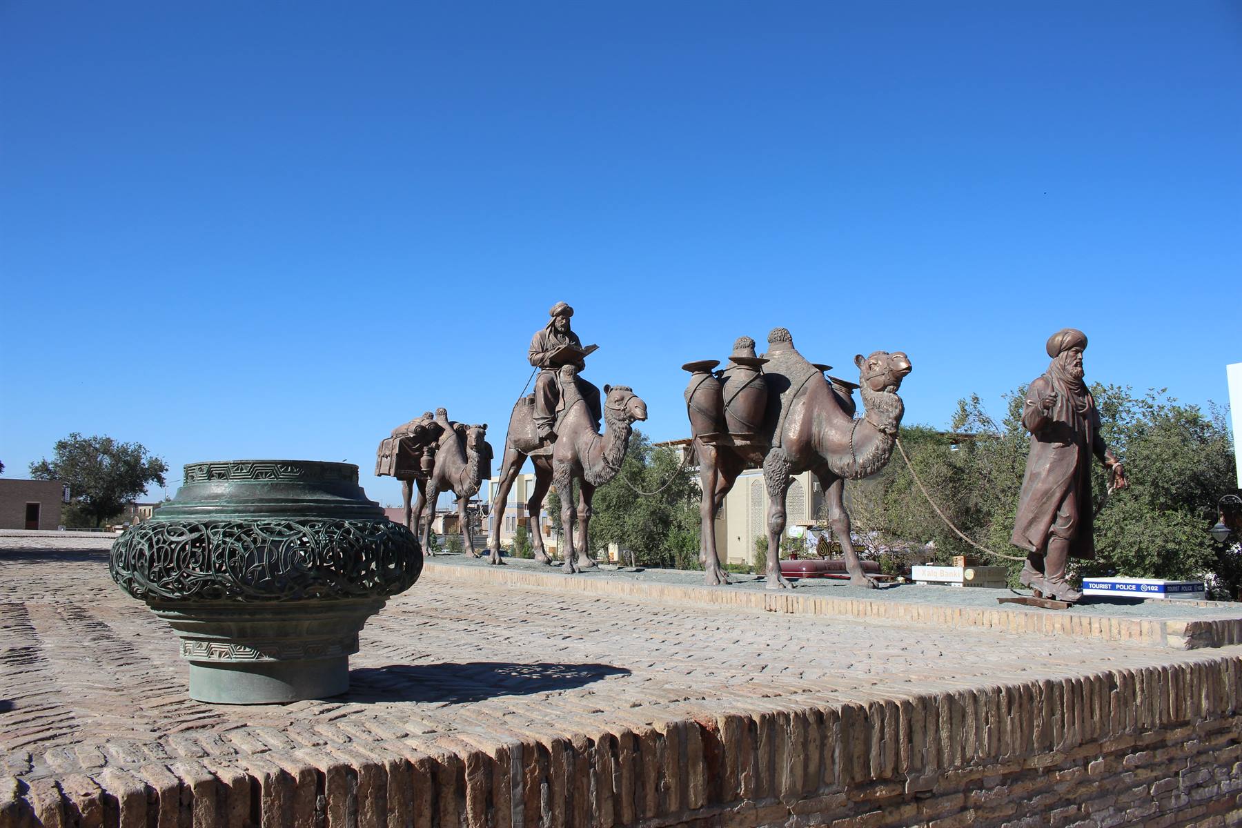 Statue bronze di cammelli e mercanti lungo il muro di mattoni, Bukhara