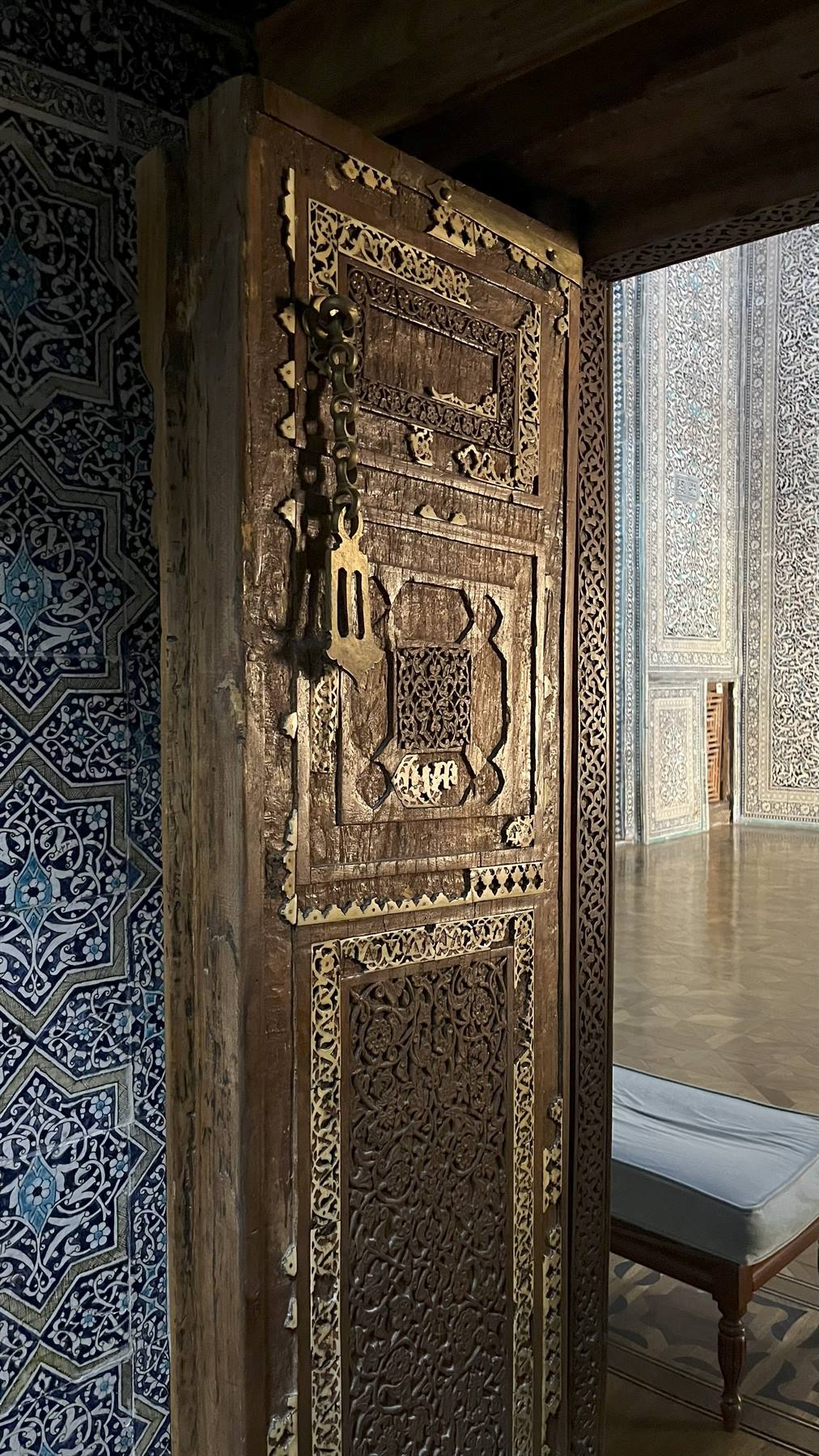 Antica porta intagliata in legno, piastrelle blu, interno di madrasa a Samarcanda