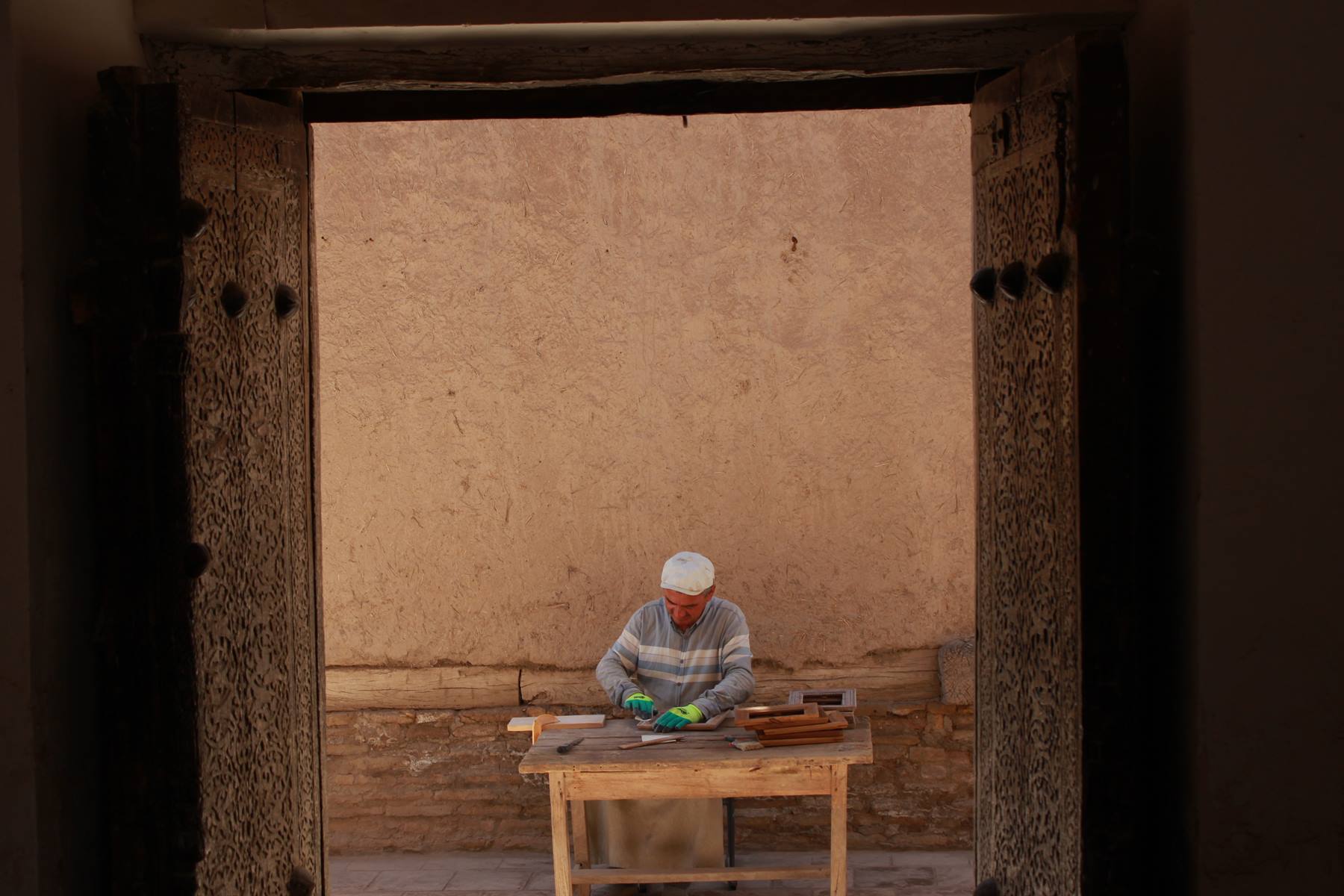 Artigiano al lavoro davanti a un muro di terra cruda a Khiva