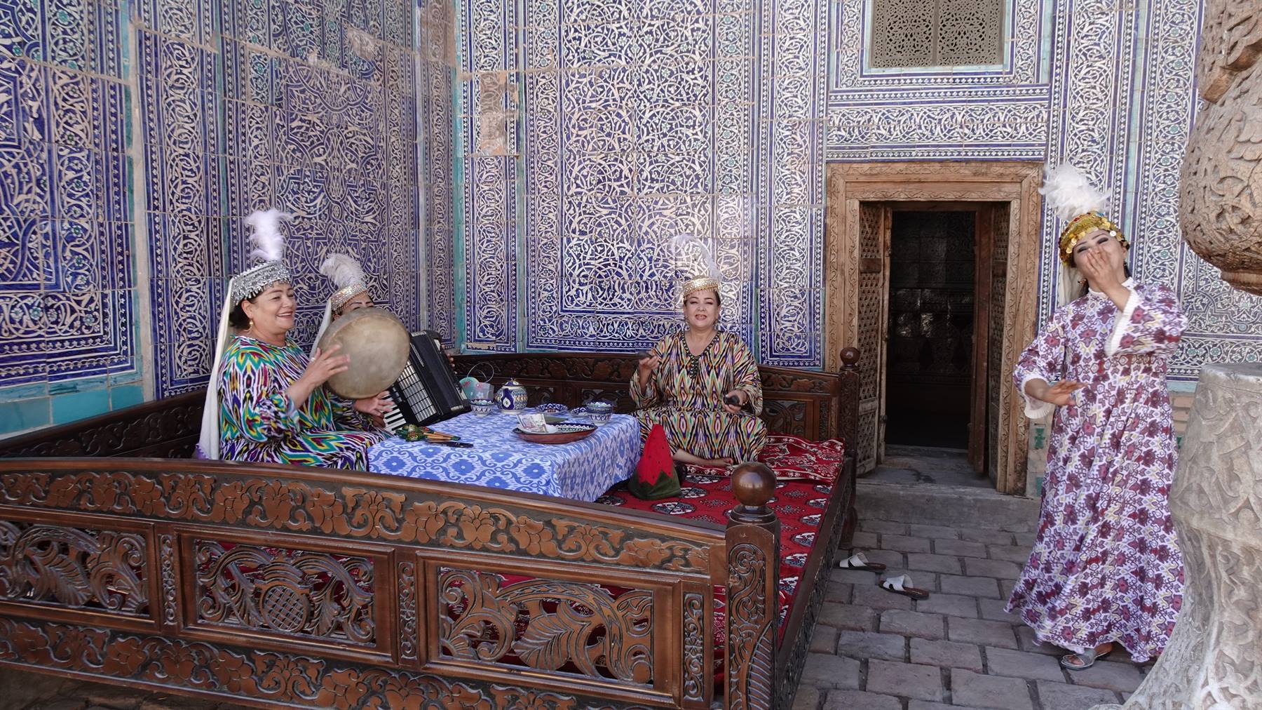 Musiciste in abiti tradizionali tra maioliche blu di Khiva