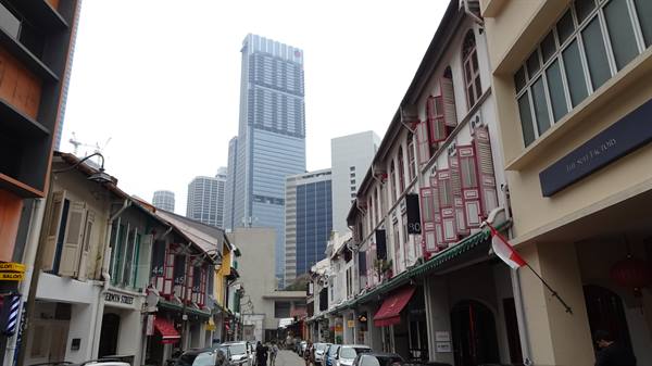 Colonial shophouses beneath Singapore skyscrapers in Chinatown, red and white flag