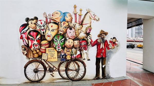 Mural: hatted vendor beside a bicycle loaded with painted masks and horses