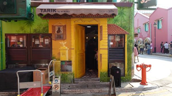 Tarik shop with painted yellow facade, red fire hydrant and colorful houses in Kampong Glam