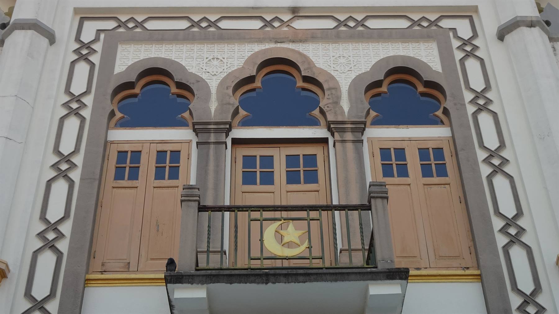 Facciata bianca con tre porte moresche, balcone e simbolo luna e stella dorato