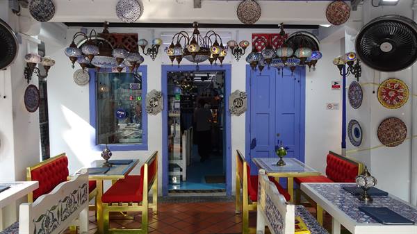 Cafe interior with Turkish mosaic glass lamps, decorative plates, tables and red benches