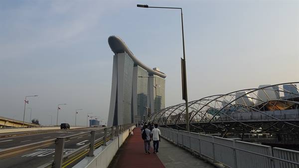 Tourists walk along the Helix Bridge toward Marina Bay Sands in Singapore