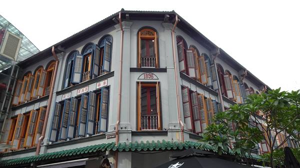 Grey 1896 colonial shophouse with colorful shutters in Chinatown
