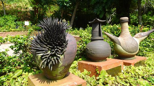 Ceramic sculptures on brick pedestals in a lush tropical garden