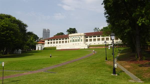 White colonial building on Fort Canning lawn, with cast-iron lampposts and tall trees