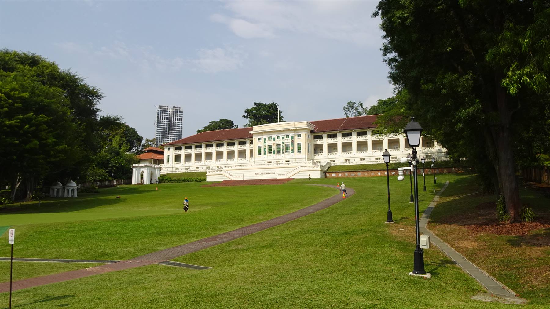 Edificio coloniale bianco sul prato di Fort Canning, con lampioni in ghisa e alberi