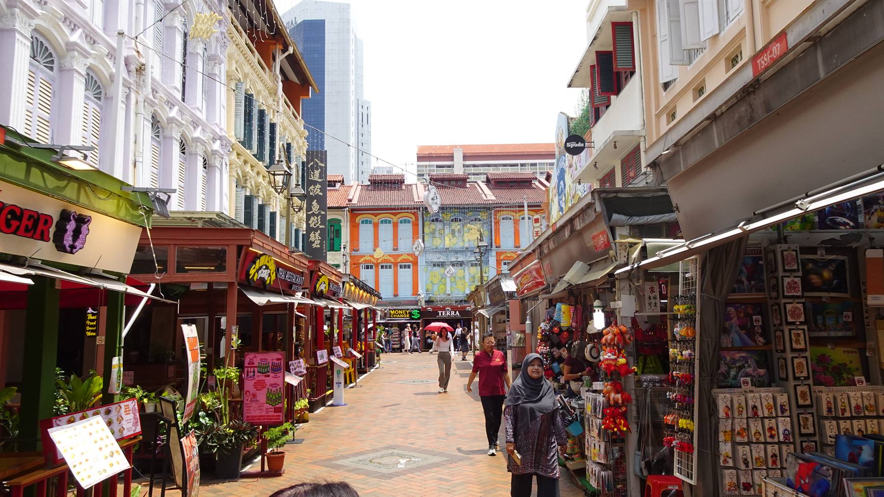 Turisti tra case a schiera colorate e bancarelle di souvenir a Chinatown, Singapore