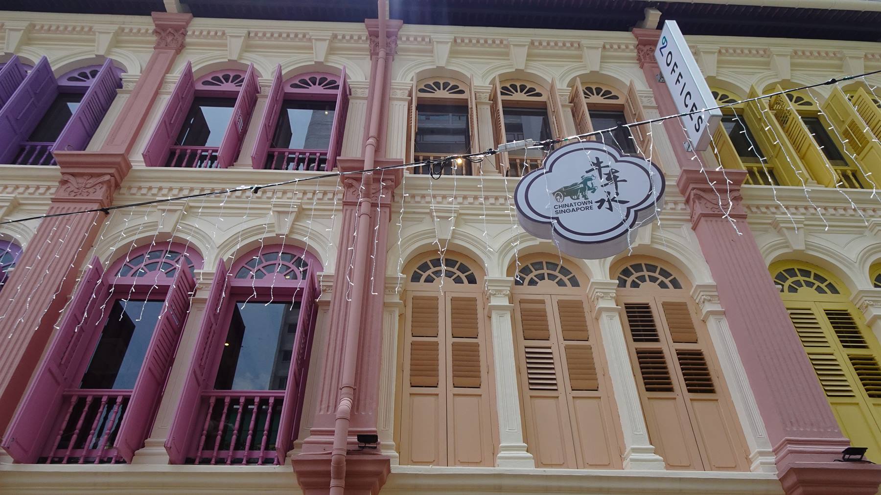 Palazzo coloniale a Chinatown con persiane rosa, gialle e arancio, insegna uffici