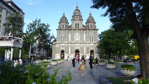Visitors stroll before the grey facade of St. Joseph's Cathedral in Beijing