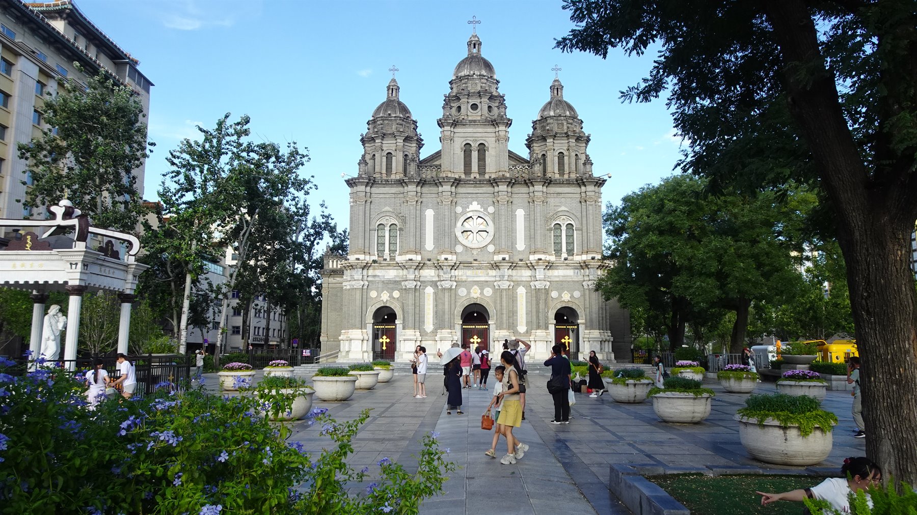 Turisti passeggiano davanti alla facciata grigia della cattedrale di San Giuseppe a Pechino