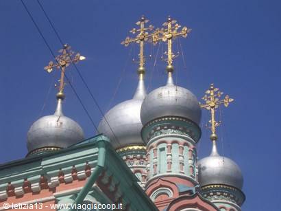 silver onion domes with golden crosses of an Orthodox church against blue sky