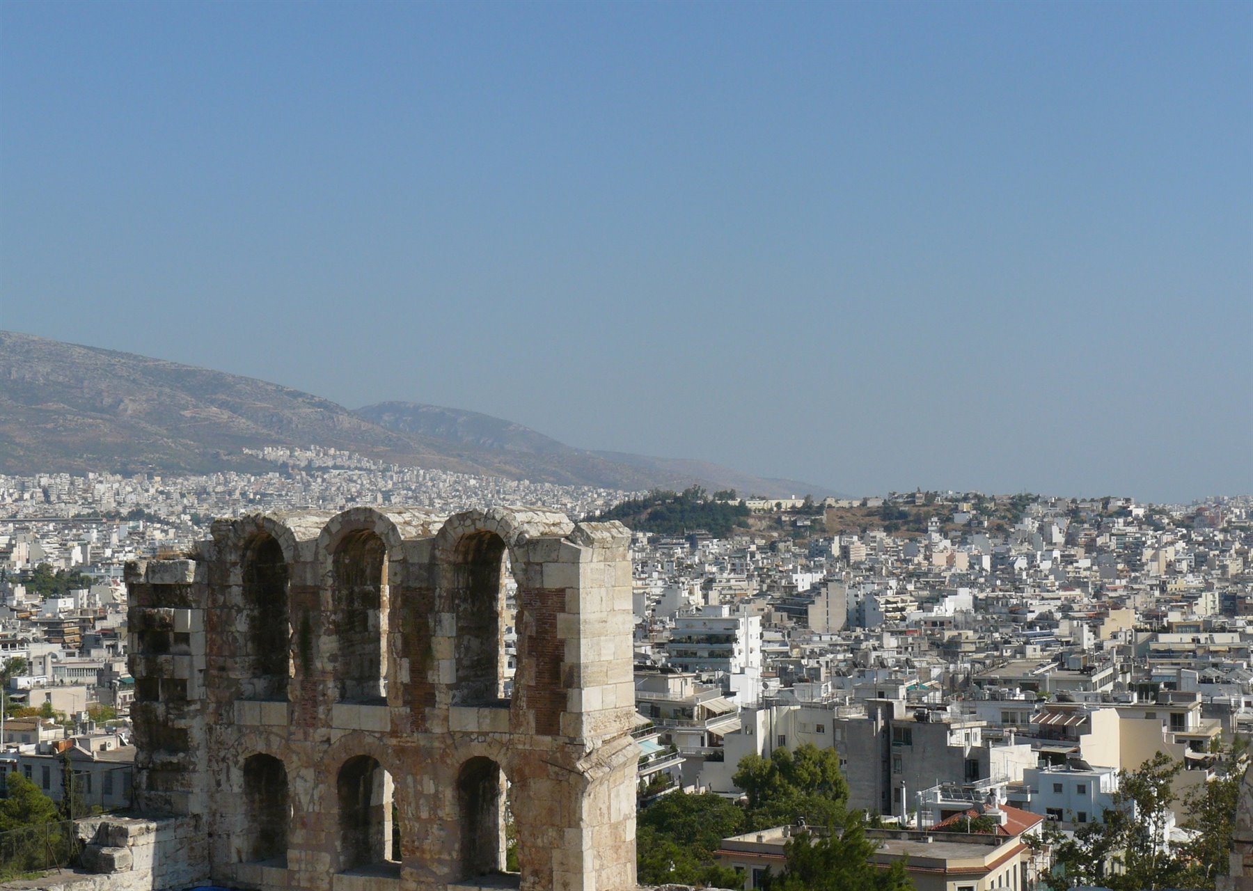 Rovina in pietra con archi davanti agli edifici bianchi di Atene
