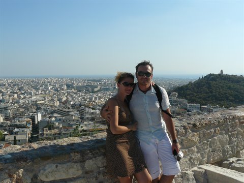Couple on the stone wall of the Acropolis, Athens and Lycabettus behind