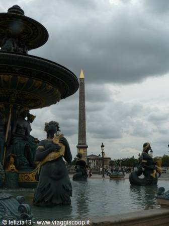 Fountain with green bronze statues and obelisk at Place de la Concorde, cloudy sky