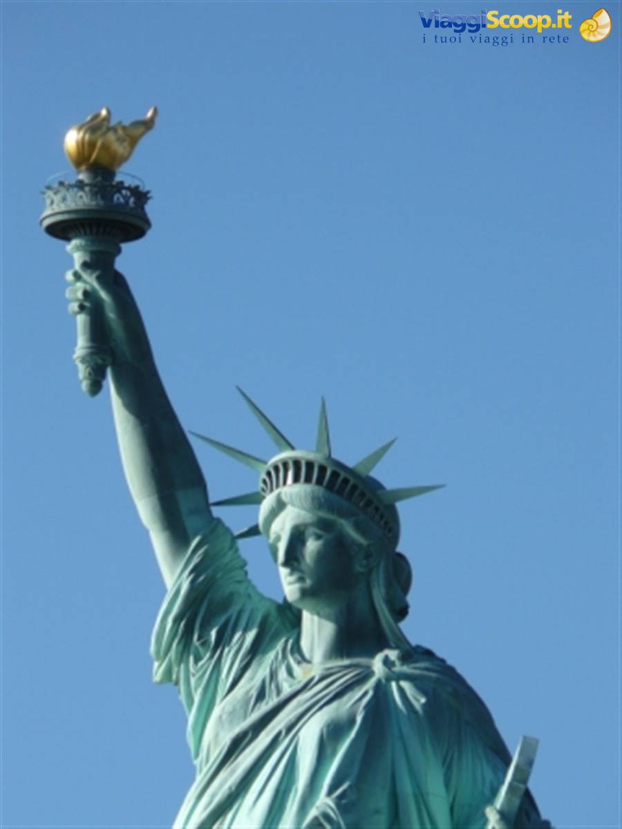 The Statue of Liberty holding her golden torch against a blue sky