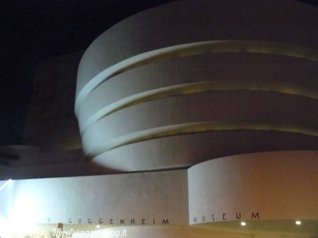 The curved concrete facade of the Guggenheim Museum illuminated at night in New York