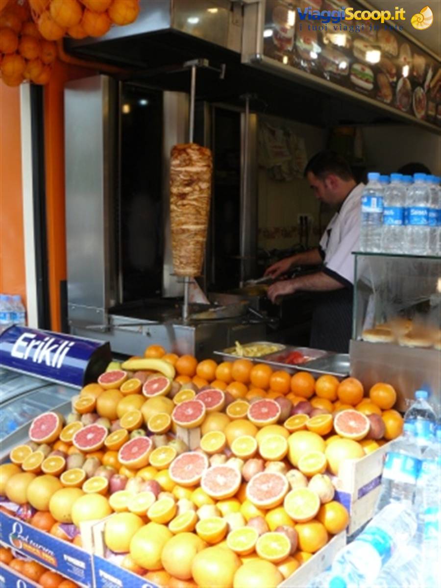 Cook slicing kebab from the spit at the stall, oranges and grapefruits in front