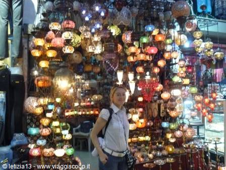 Woman in white among hundreds of colorful Turkish lanterns hanging in a bazaar shop