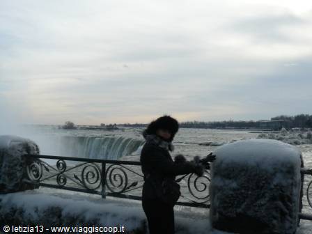 Tourist leaning on the snowy railing in front of the frozen Niagara Falls