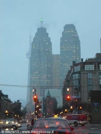 Foggy skyscrapers with CN Tower behind, traffic and red lights in Toronto