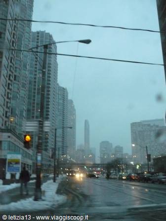 Snowy skyscrapers along the wet street, Toronto's CN Tower looming in fog