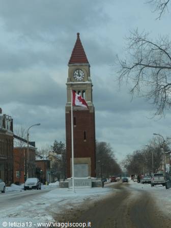 Red brick clock tower with Canadian flag, snowy winter street