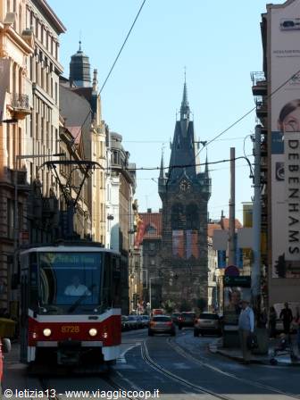 Red and white tram crosses busy street toward Prague's iron tower