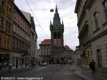 St. Henry's Tower rising between Prague buildings, tram wires above the street