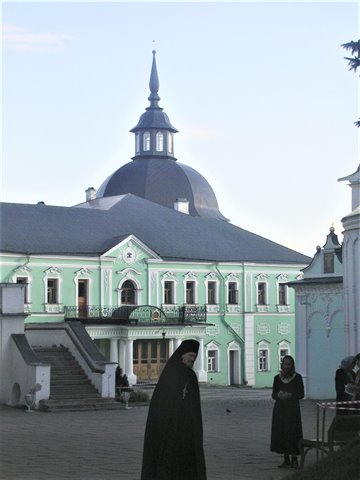 Nuns in black walk through a monastery courtyard with green domed building