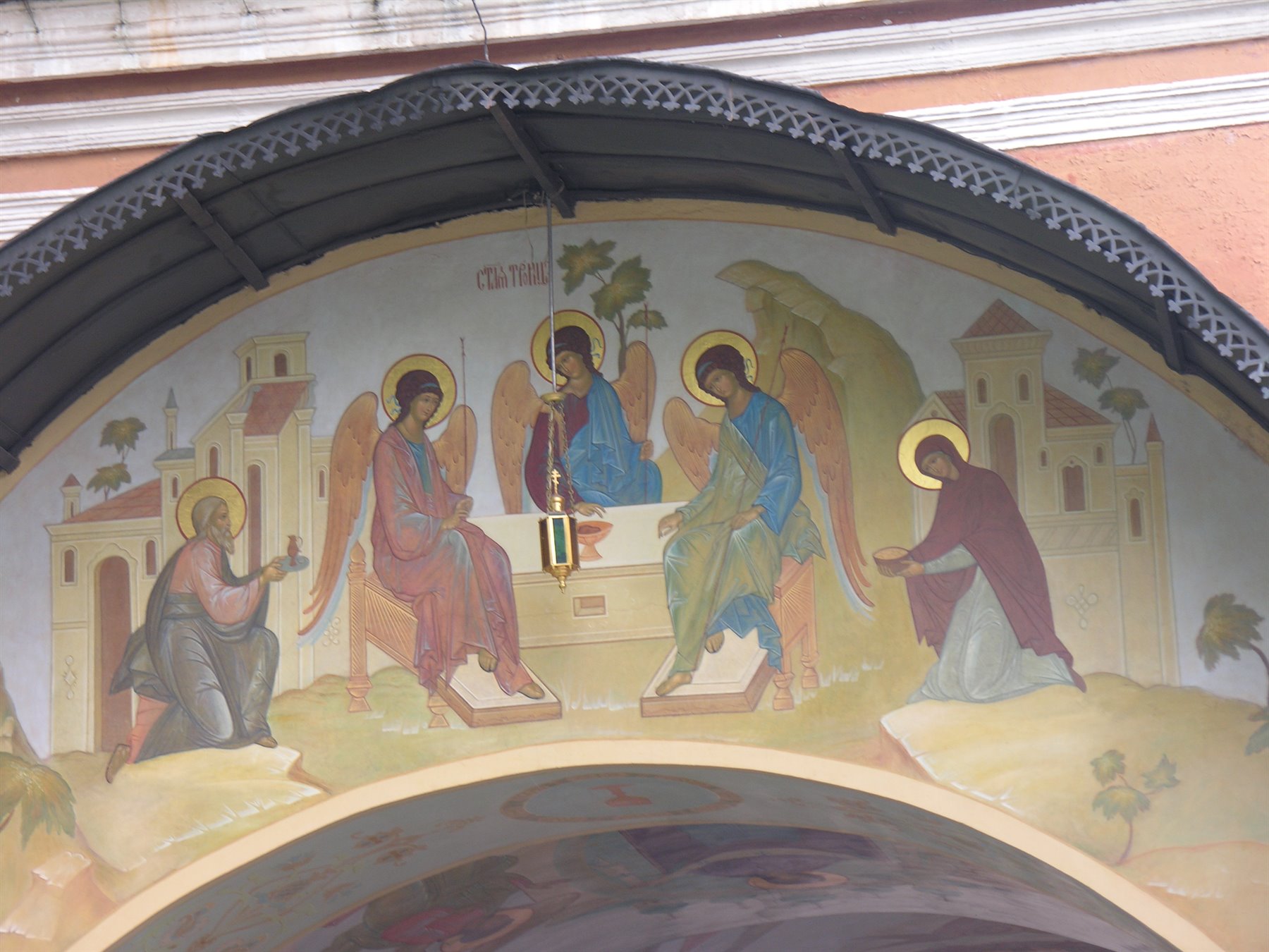 Affresco della Trinità con tre angeli al tavolo, sopra un ingresso di chiesa