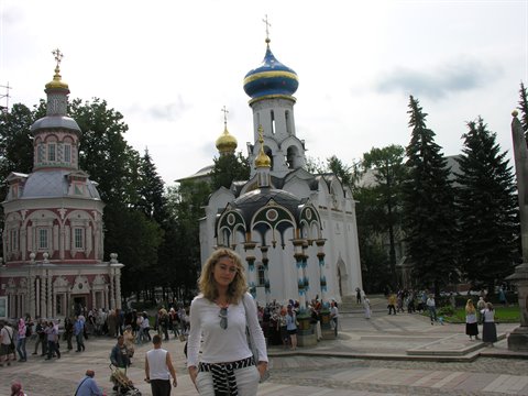 Blonde woman in front of blue and golden onion domes at Sergiev Posad Lavra