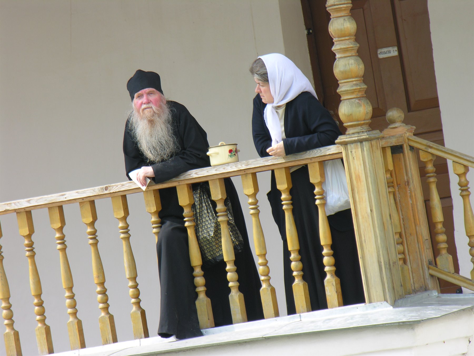 Monaco ortodosso e suora parlano sul ballatoio in legno di un monastero