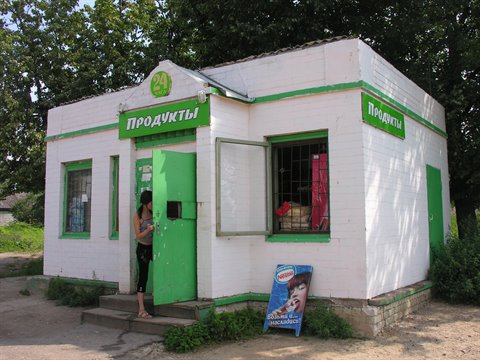 Woman at the entrance of a Russian grocery store, white and green brick building