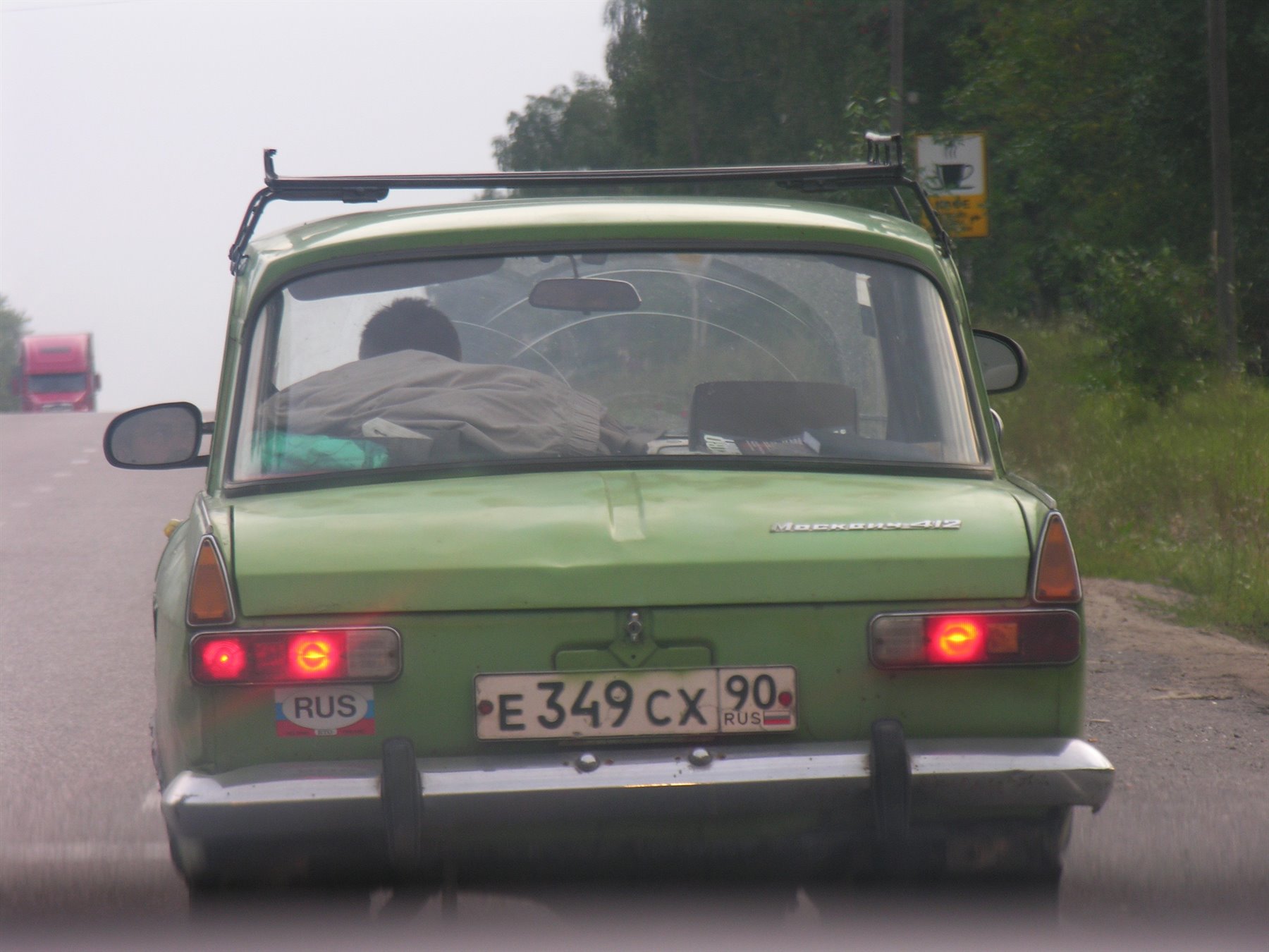 Auto verde russa ferma su strada di campagna, freni accesi, targa E349CX