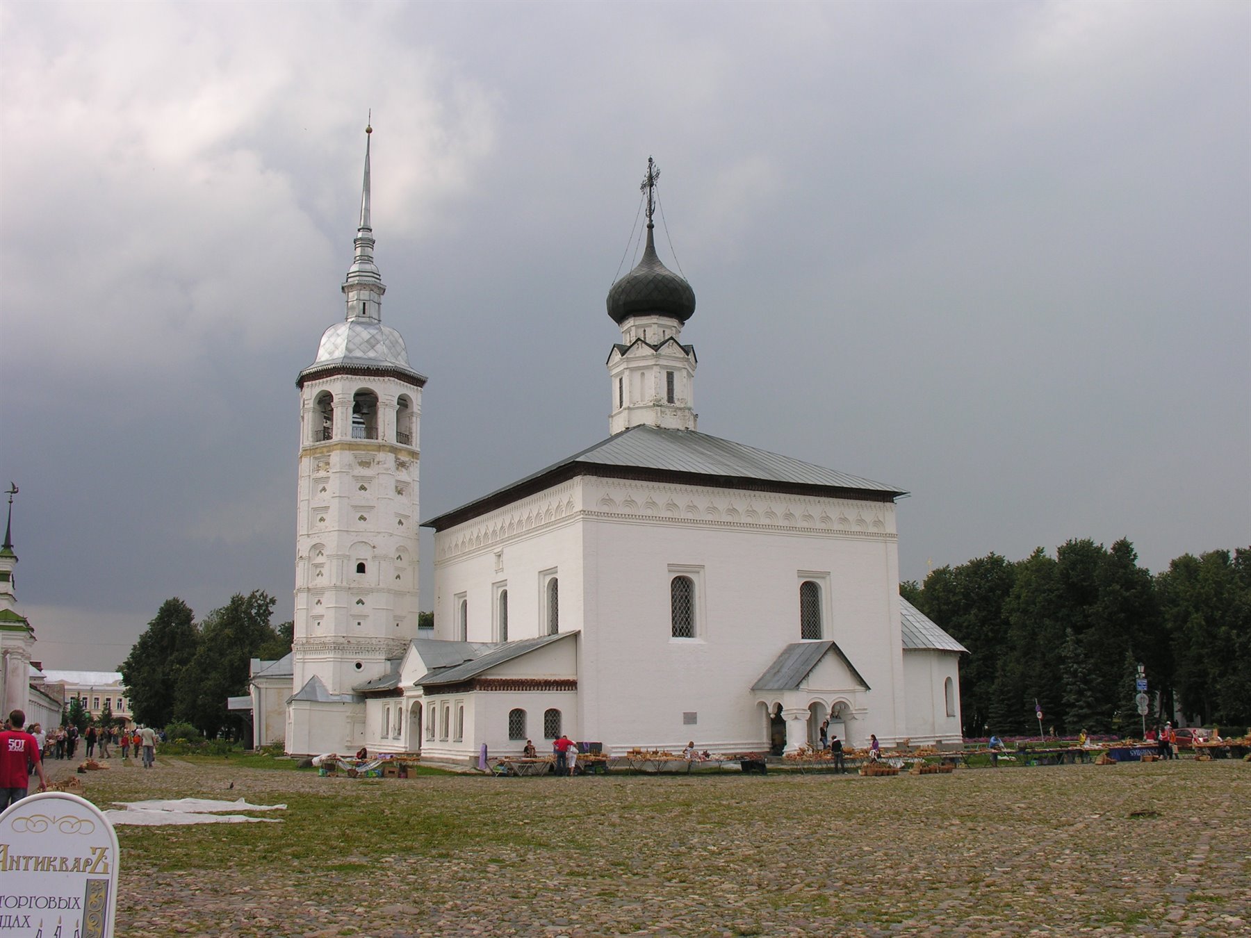 Chiesa bianca con cupola scura e campanile a Suzdal sotto cielo nuvoloso