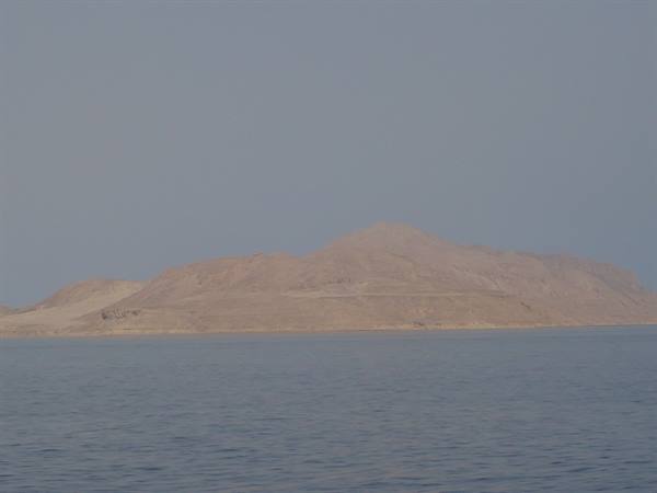 Arid rocky island rising from the Red Sea under hazy sky