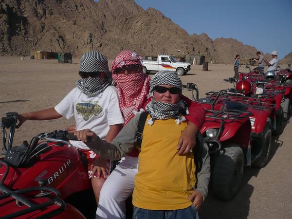 Tourists in keffiyeh scarves on red Yamaha quads in rocky desert