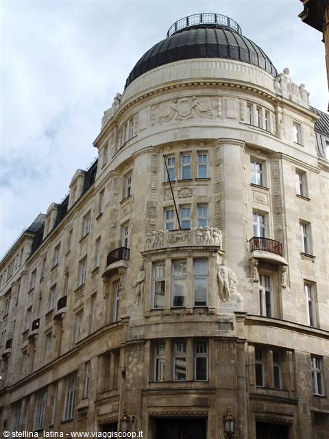 Art Nouveau building with glass dome and stone sculptures in daylight