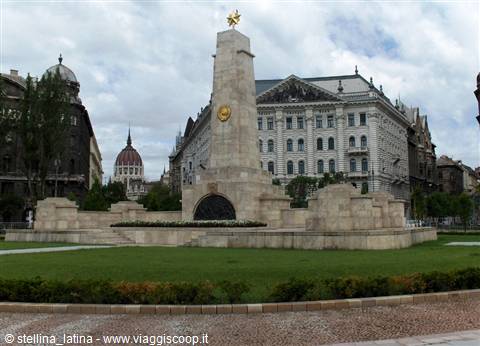 Stone war memorial with golden star in Budapest, on a green lawn