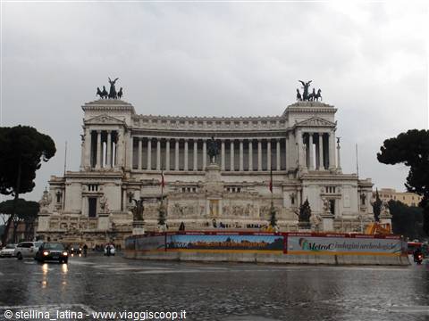 The Vittoriano monument in Rome under grey sky, traffic on wet streets