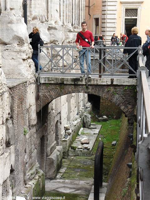 Tourist on metal footbridge over ancient brick and stone ruins in Rome