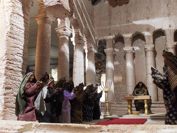 Nativity figurines inside a salt-carved temple: columns, golden menorah, praying figures