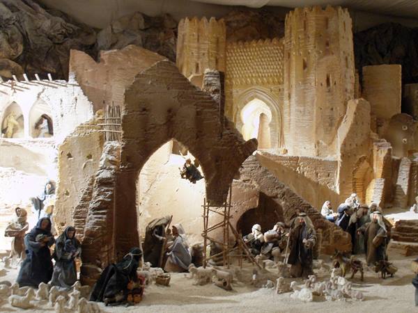 Nativity scene with figurines among sandy ruins and castle, warm light