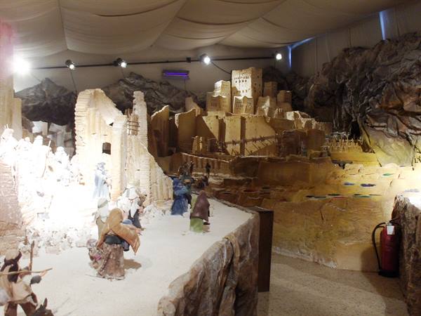 Mechanical nativity scene with terracotta figurines, papier-mâché village lit by spotlights