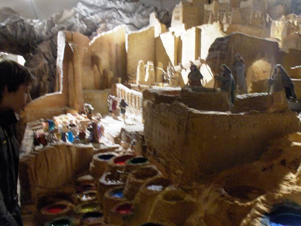 Boy observes a large nativity scene with figurines among papier-mâché houses