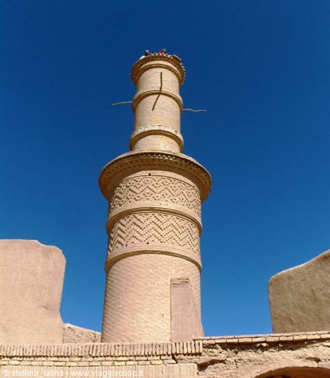 Brick clay minaret with zigzag patterns against a deep blue sky